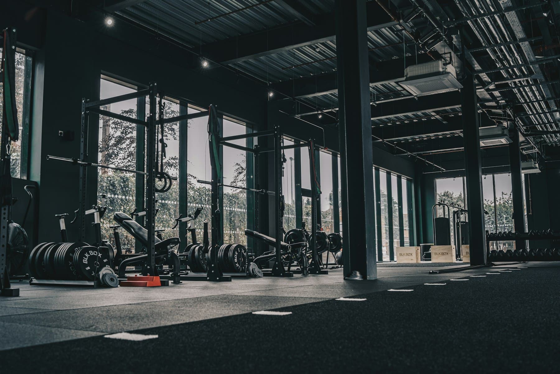 Gimnasio comercial amplio con racks, discos y ventanales