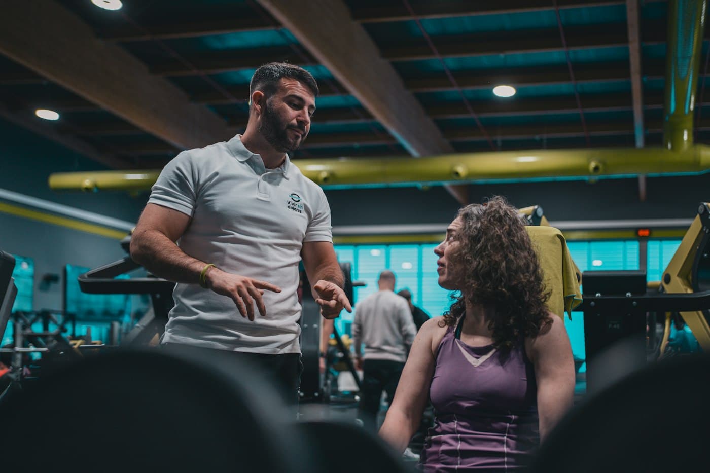 Asesor conversando con una clienta en la sala de un gimnasio